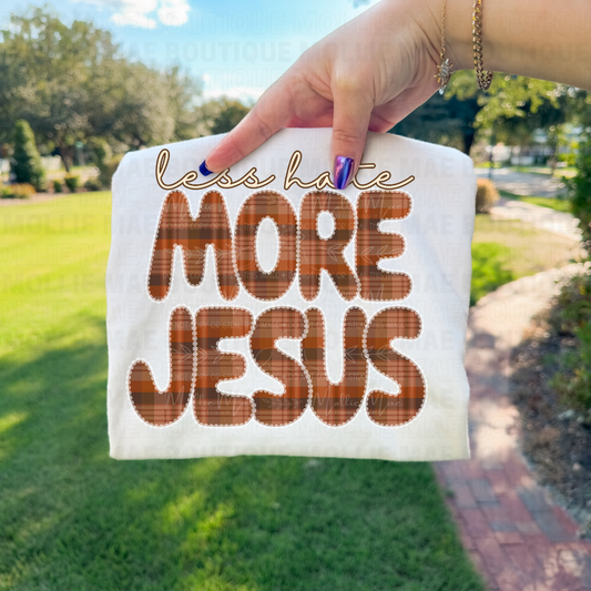 Closeup of Less Hate More Jesus tee design displayed outdoors.