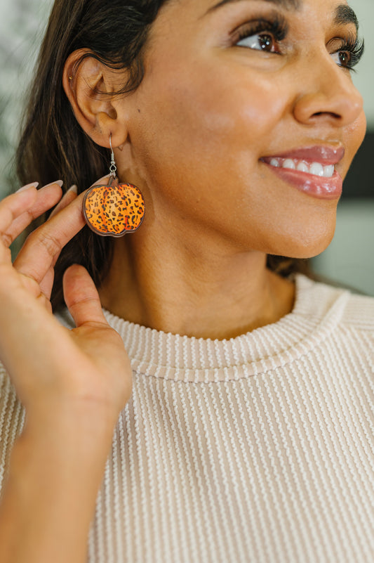 Woman wearing a pair of orange earrings, smiling.