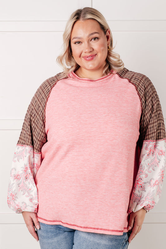 Woman wearing a pink sweater with floral sleeves against a white background