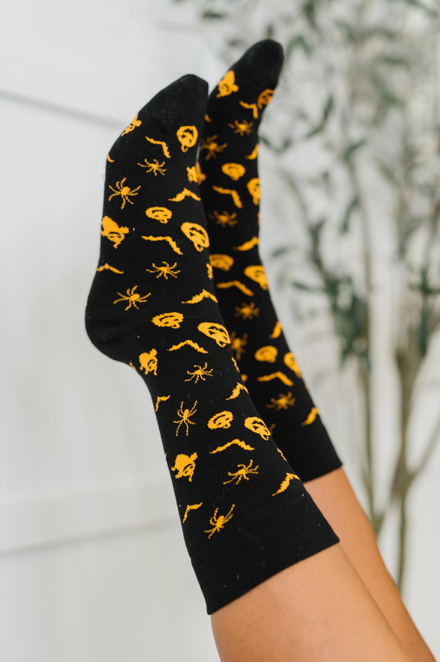 Black socks with yellow spider pattern held against a neutral background