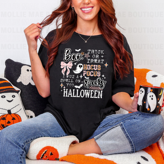 Woman wearing Spooky Quotes Graphic Tee on black Gildan Softstyle, sitting with Halloween-themed decor.