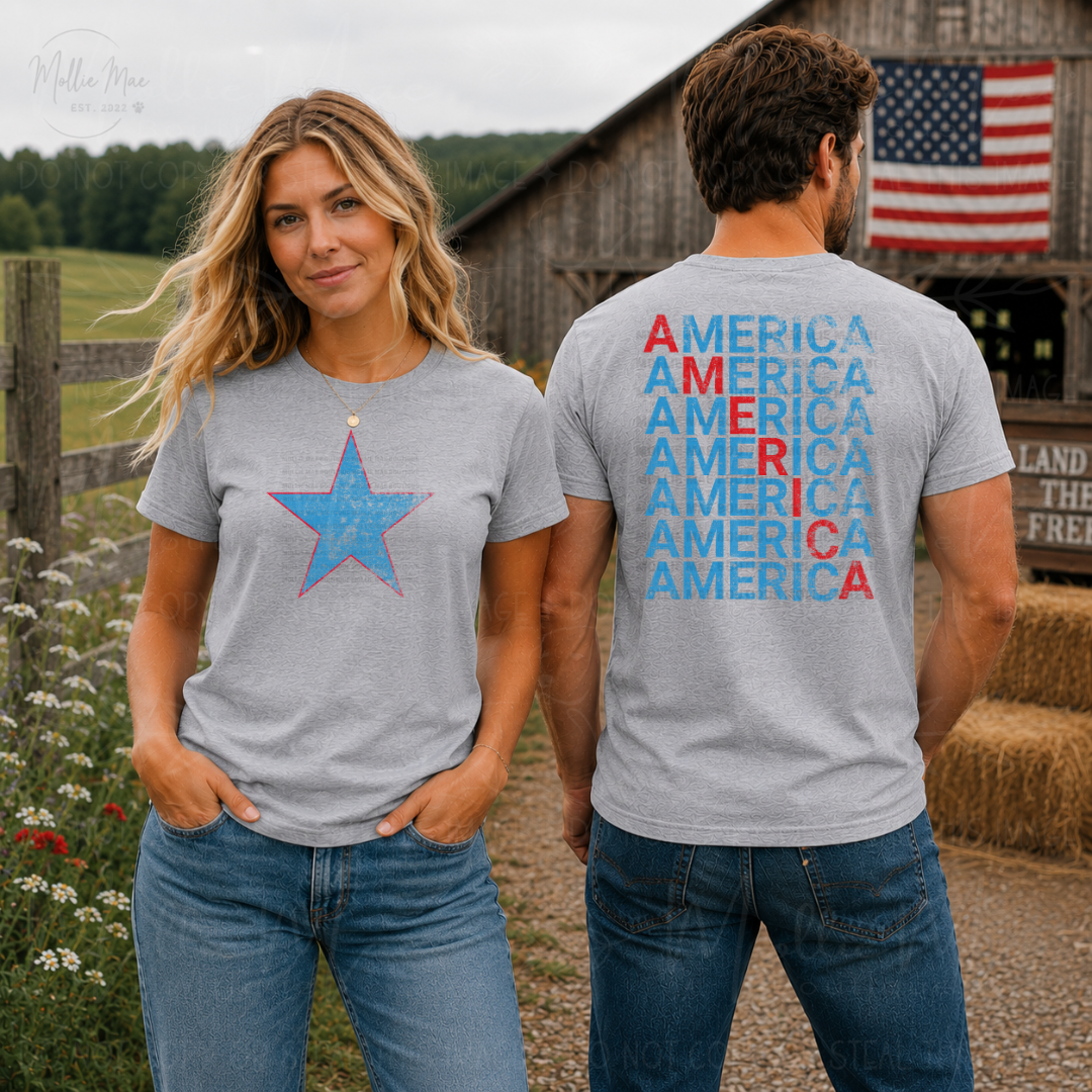 Two people wearing gray t-shirts with a blue star and 'AMERICA' text, standing in front of a barn with an American flag.