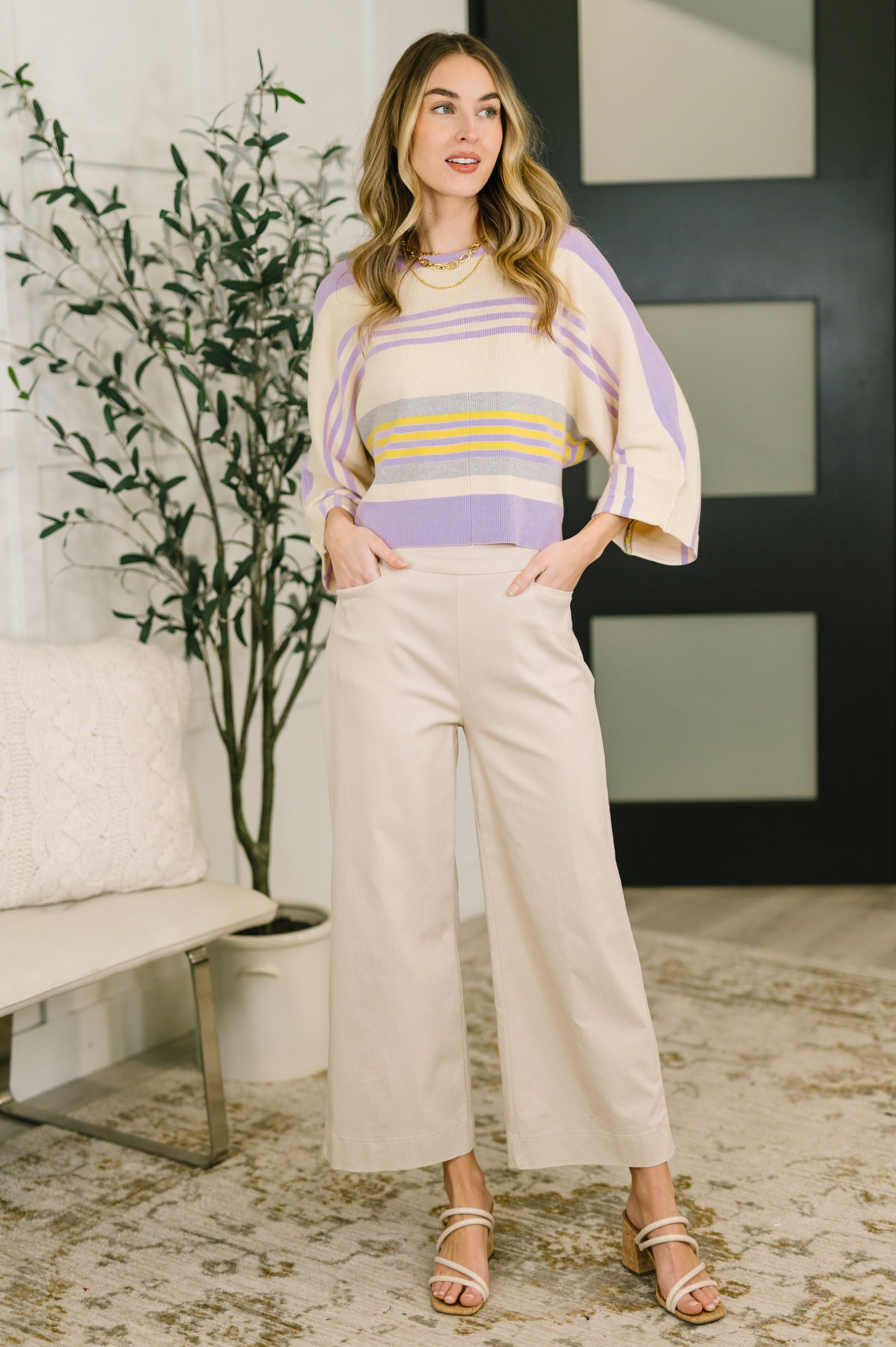 Woman wearing a striped sweater and wide-leg pants in a living room setting