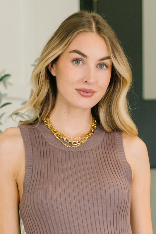Woman wearing a gold necklace with a neutral background