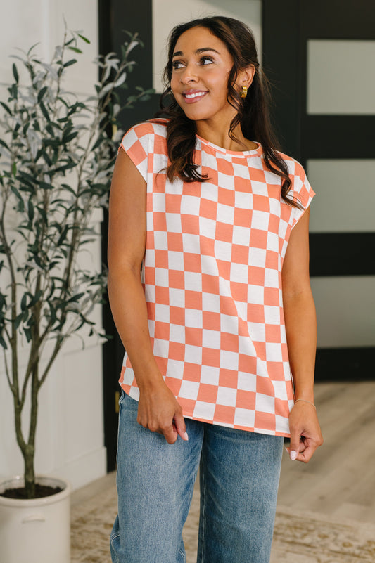 Woman wearing a checkered shirt and jeans indoors with a plant in the background