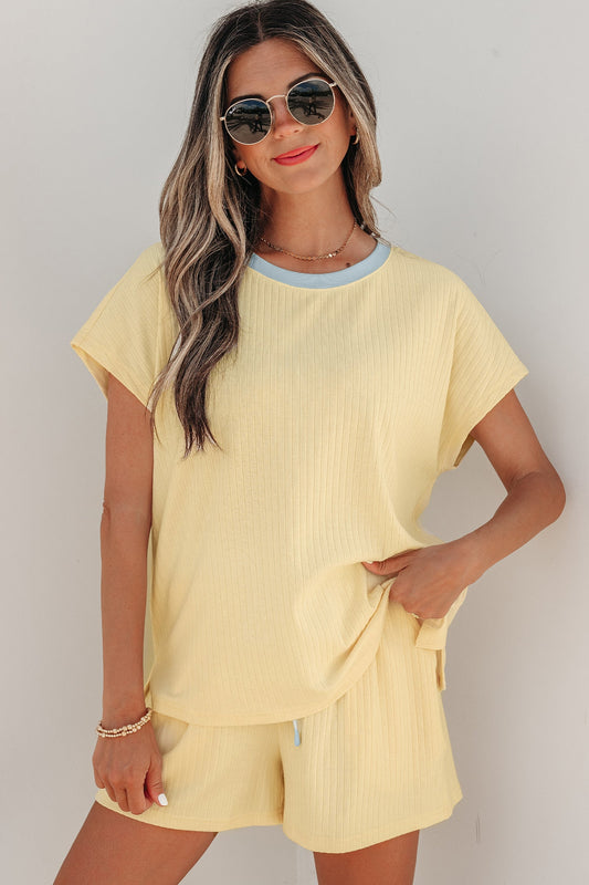 Woman wearing a yellow outfit with sunglasses against a plain background