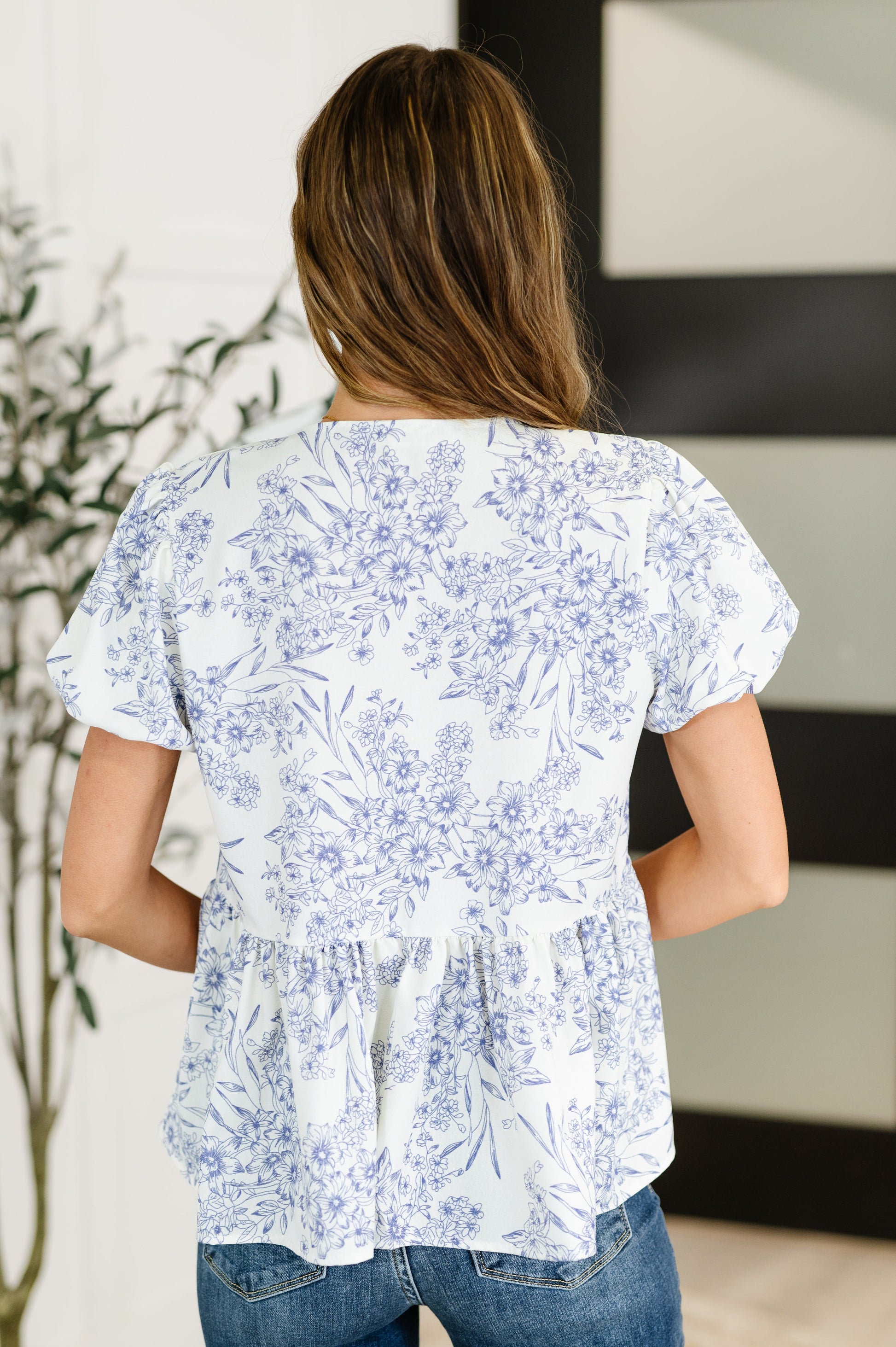 Woman wearing a white blouse with blue floral pattern in an indoor setting