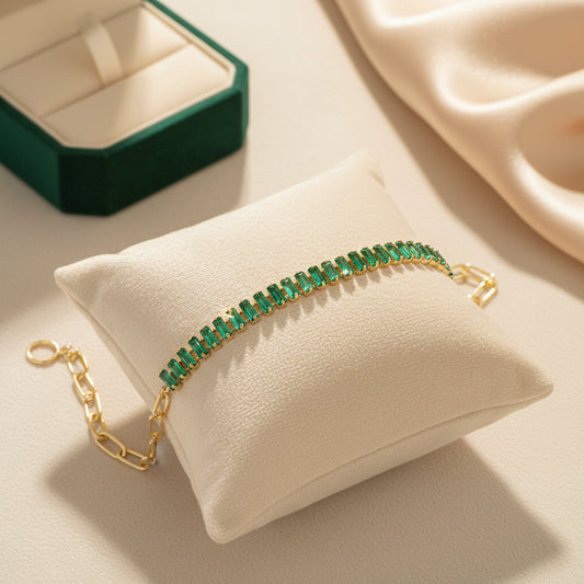 Gold bracelet with green beads on a beige background