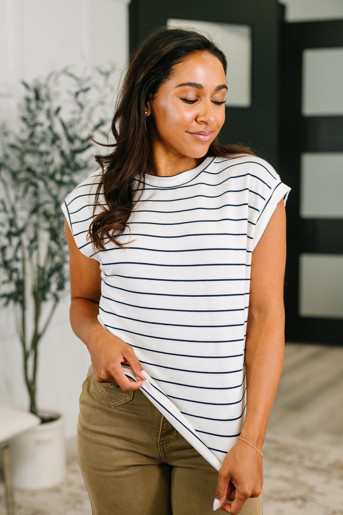 Woman wearing a striped shirt and holding a piece of paper indoors.