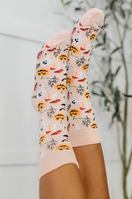 Colorful socks with pumpkins and leaves pattern worn by a person against a blurred background