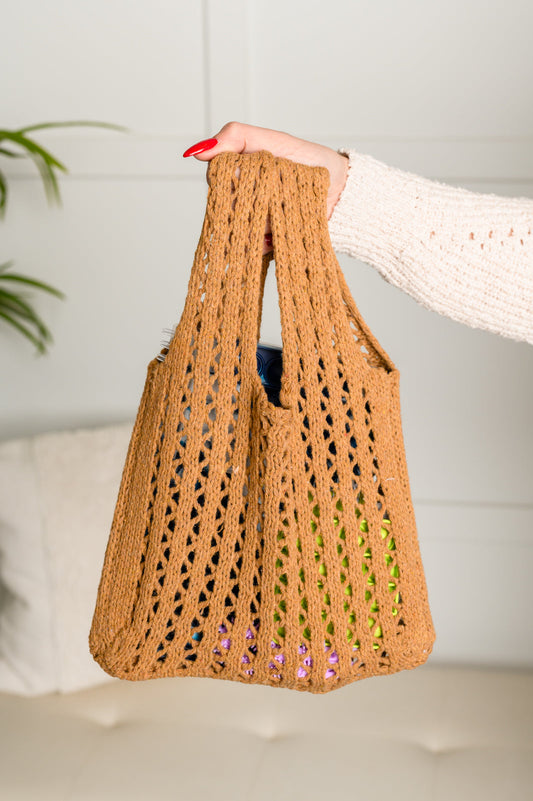 Brown woven bag held by a person with a white background