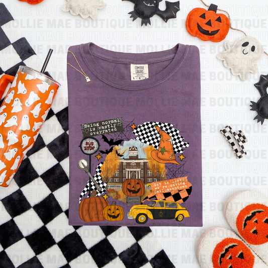 Flat lay of Halloweentown graphic tee in wine Comfort Colors with Halloween collage print and pumpkins.