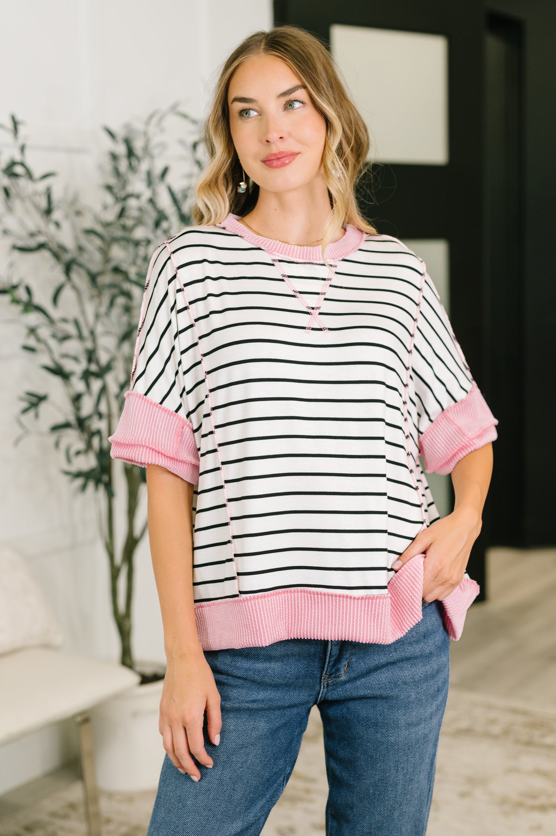 Woman wearing a black and white striped shirt with pink accents in an indoor setting.