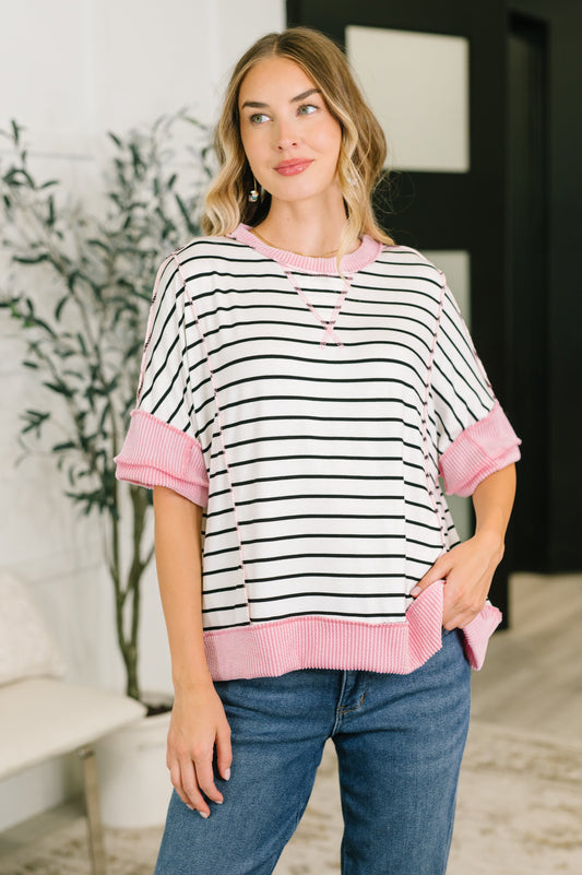 Woman wearing a black and white striped shirt with pink accents in an indoor setting.