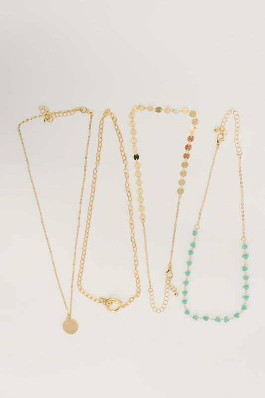 Set of four gold necklaces with different designs on a light gray background