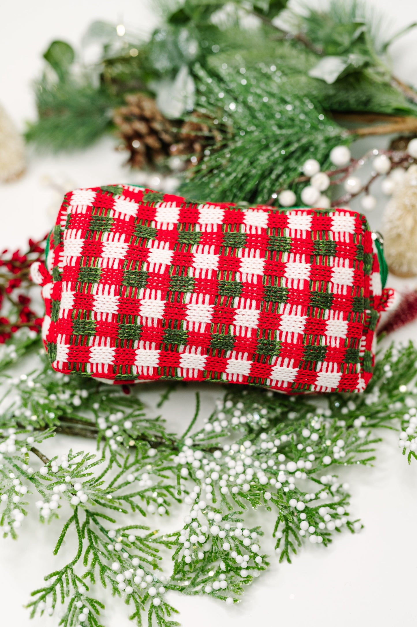 Red and green checkered pouch on a snowy background with pine branches