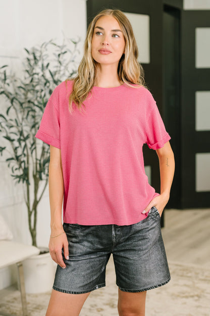 Woman wearing a pink top and denim shorts indoors