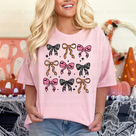 Person wearing a pink t-shirt with bow designs in a Halloween-themed setting