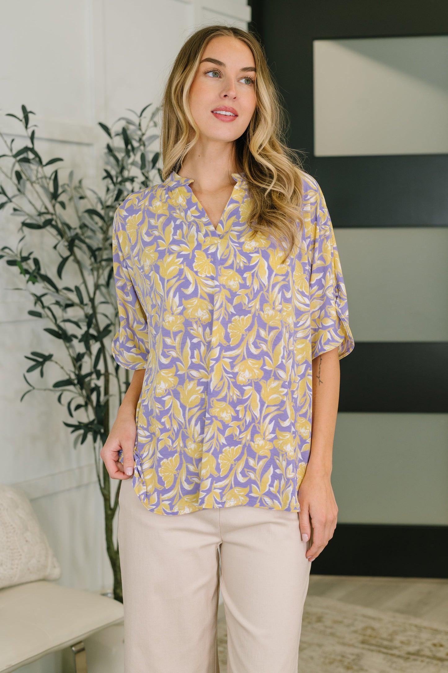 Woman wearing a yellow and purple patterned blouse in an indoor setting.