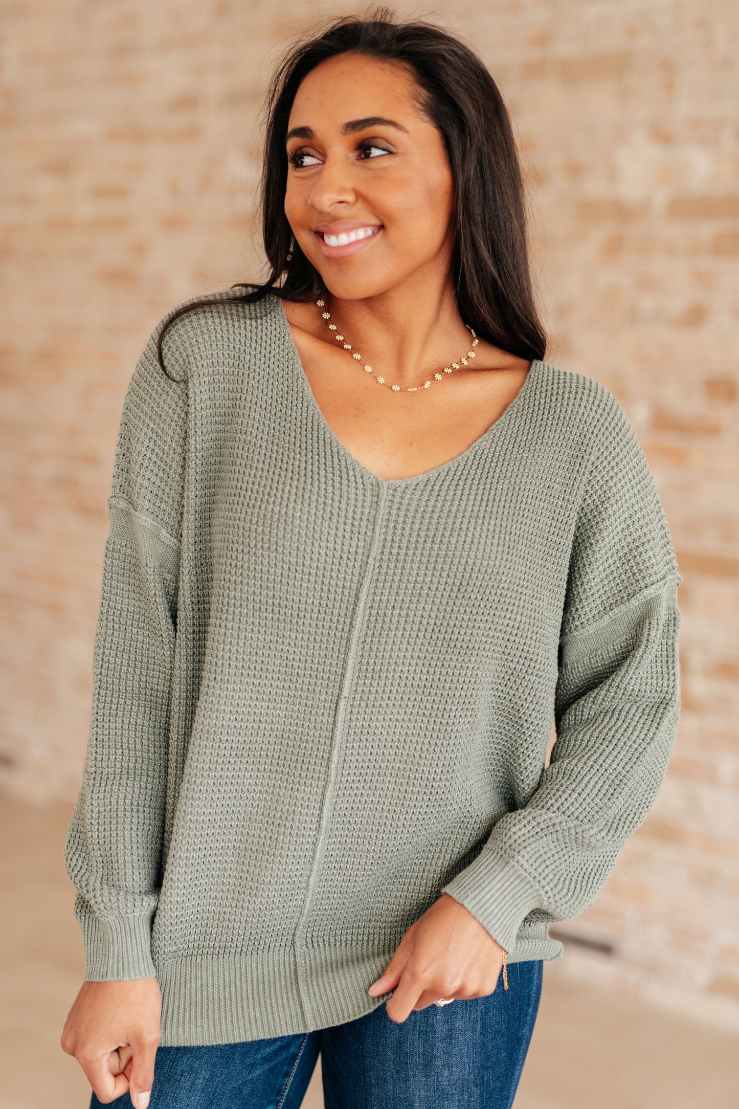 Woman wearing a green sweater against a beige wall