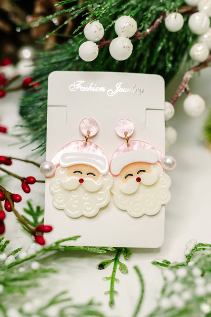 Santa Claus earrings on a card with Christmas decorations in the background