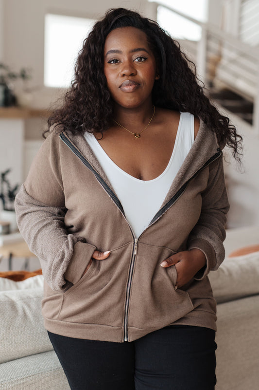 Woman wearing a beige zip-up hoodie in a casual indoor setting