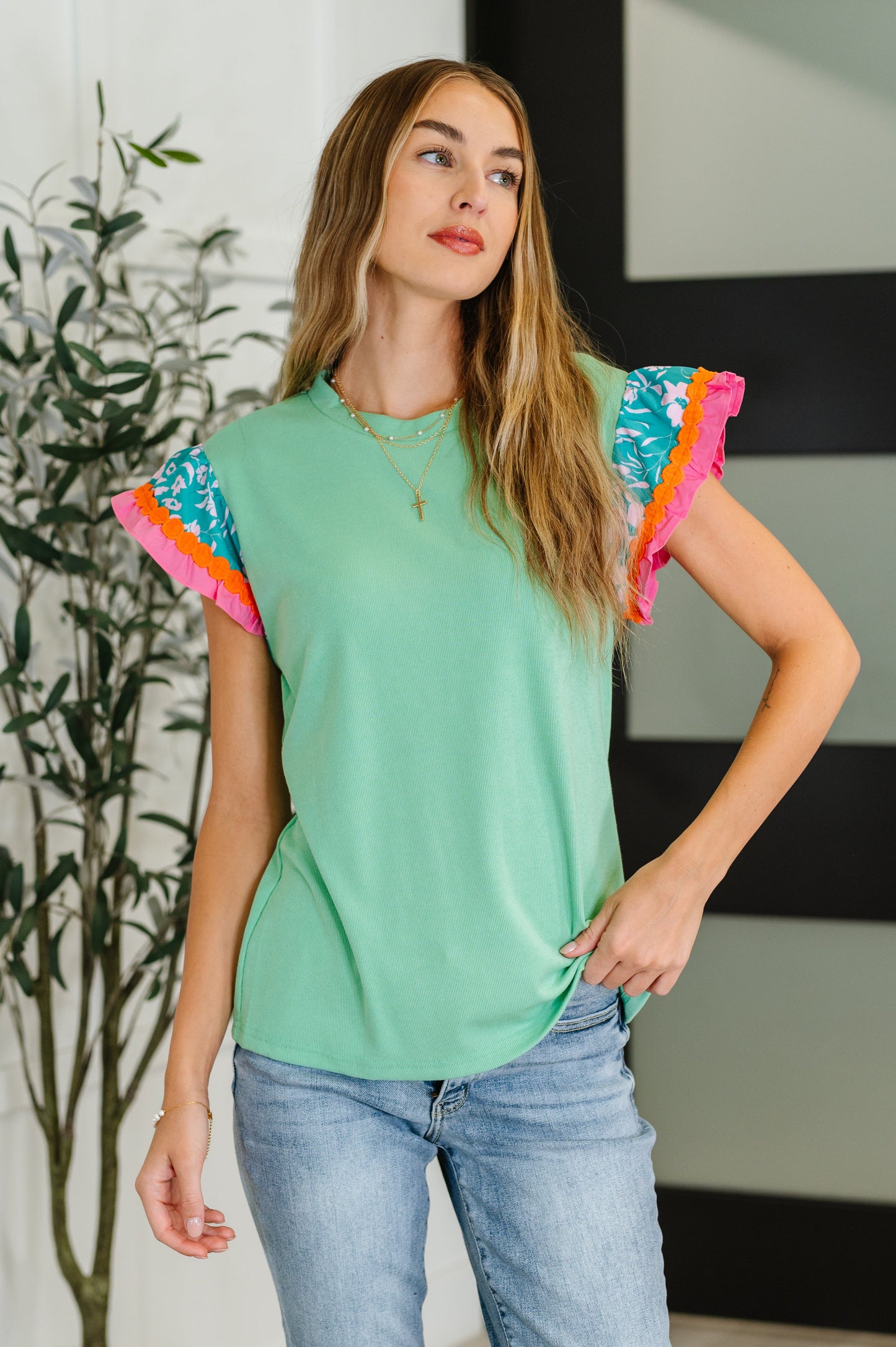 Woman wearing a green top with colorful sleeves in an indoor setting