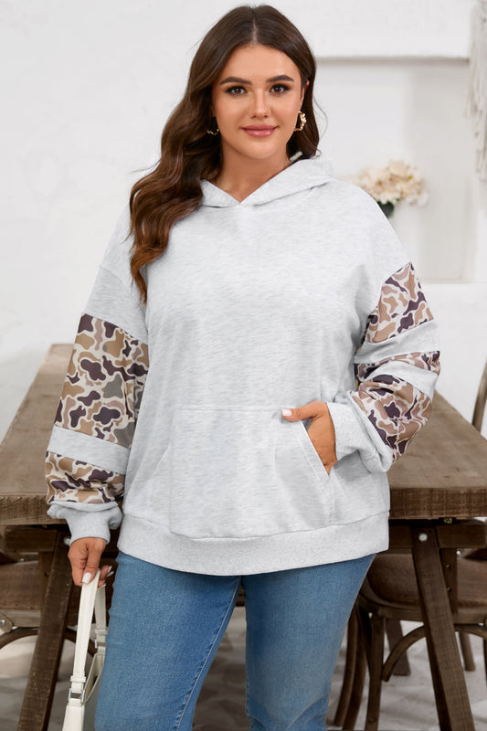Woman wearing a light gray hoodie with leopard print sleeves in a casual setting.