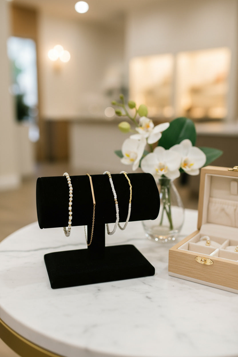 Two pairs of gold hoop earrings on a black stand against a white background