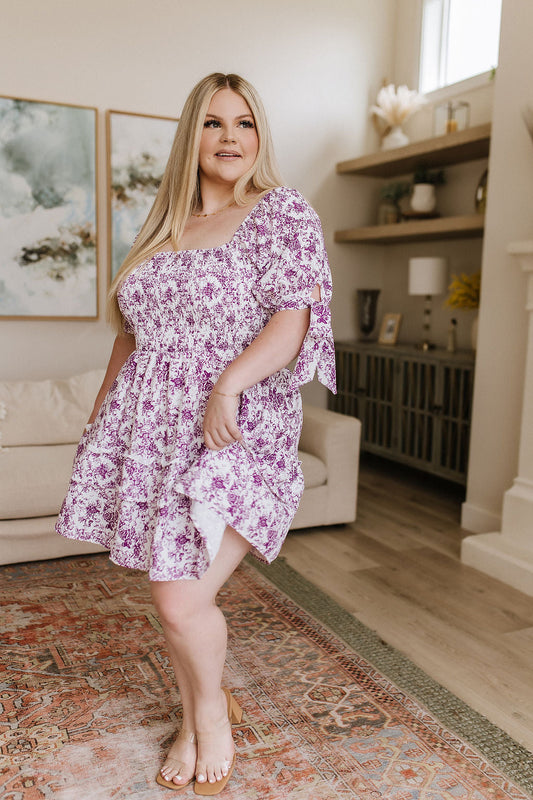 Woman in a floral dress standing in a living room.