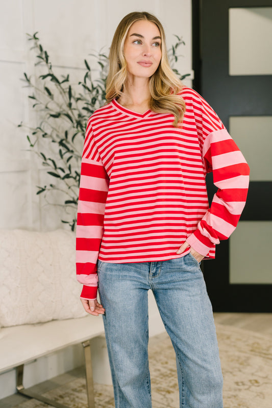 Woman wearing a red and white striped sweater and blue jeans indoors.
