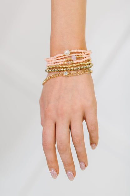 Hand wearing multiple bracelets on a plain background