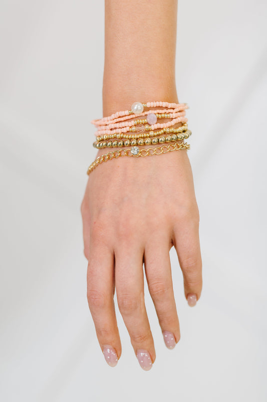Hand wearing multiple bracelets on a plain background