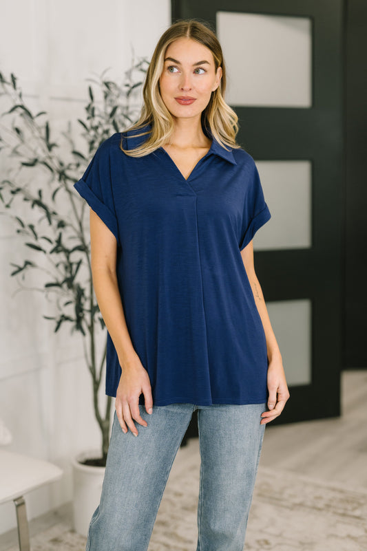 Woman wearing a blue top and light blue jeans indoors.