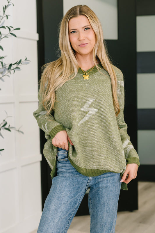 Woman wearing a green sweater with a lightning bolt design, standing indoors.