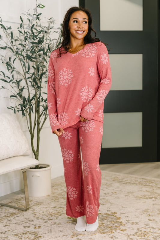 Woman wearing a pink pajama set with white floral patterns in a home setting.