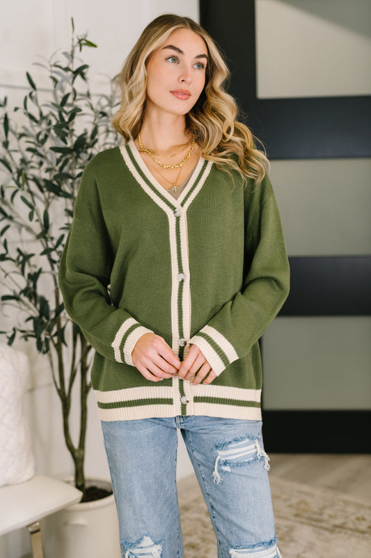 Woman wearing a green cardigan with white trim in an indoor setting
