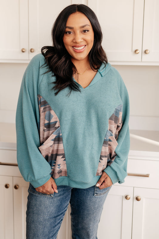 Woman wearing a teal sweater with plaid sleeves in a kitchen setting