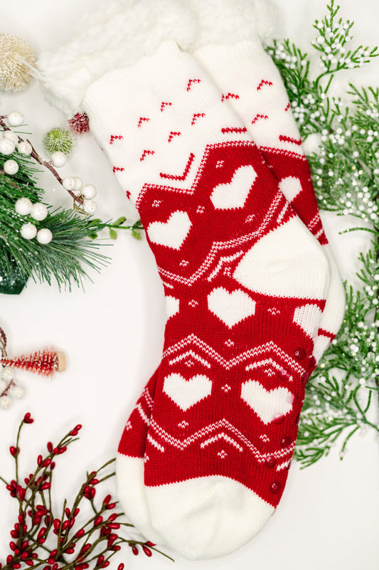 Red and white patterned socks with Christmas decorations on a white background