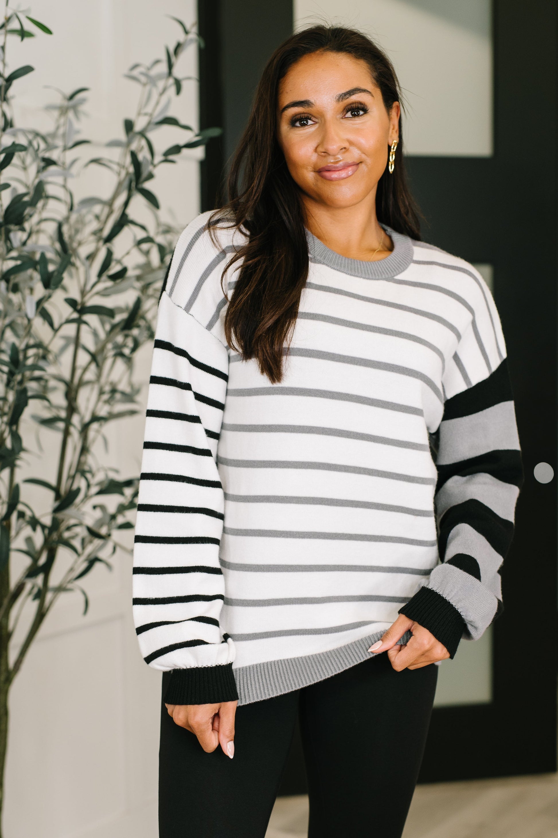 Woman wearing a black and white striped sweater with a blurred indoor background