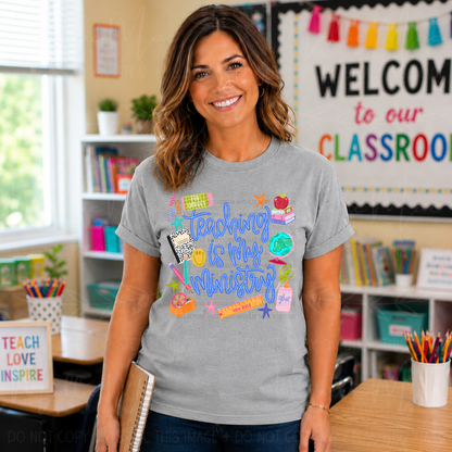 Teacher wearing a gray t-shirt with colorful text in a classroom setting