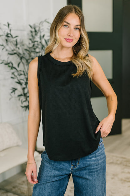 Black sleeveless top worn by a person with a neutral background