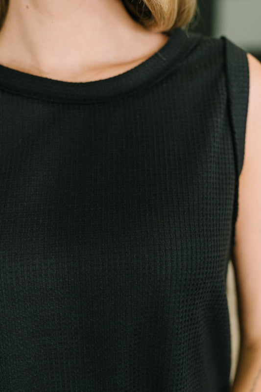 Black sleeveless top worn by a person with a neutral background