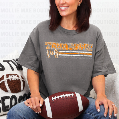 Woman wearing Tennessee Vols Stripe Graphic Tee on charcoal Gildan shirt holding football.