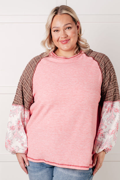 Woman wearing a pink sweater with floral sleeves against a white background