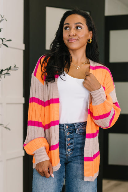 Woman wearing a colorful striped cardigan with a white top and blue jeans.