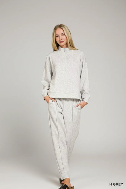 Lady wearing a jogging suit, light grey. 