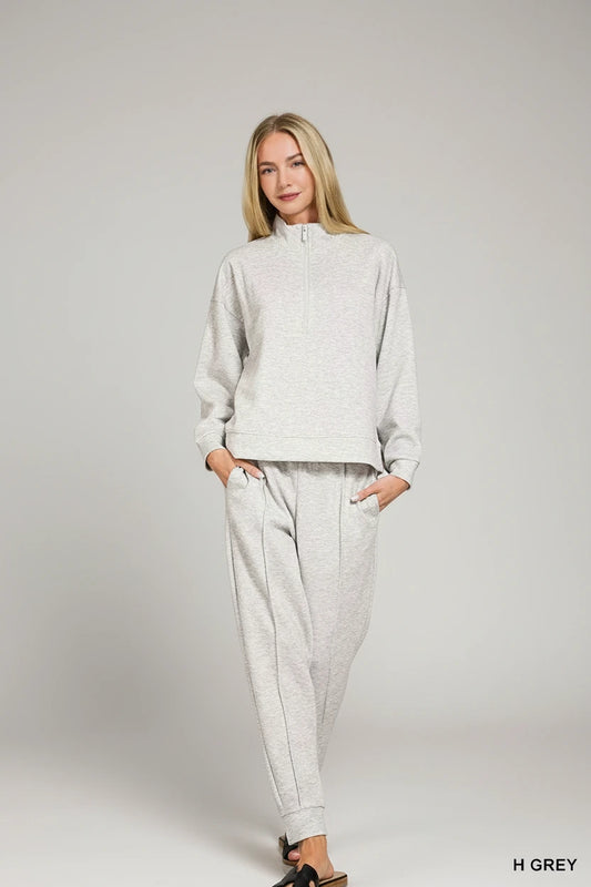 Lady wearing a jogging suit, light grey. 